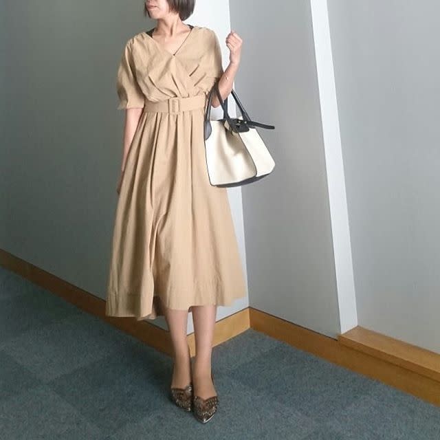 ベージュフレアワンピースと白のハンドバックとブラウンのパンプスのコーデ