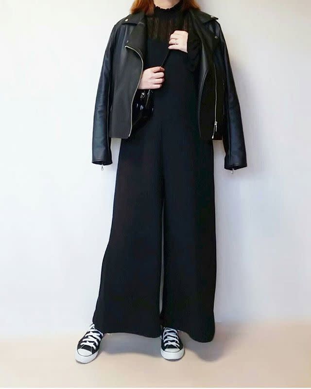 レザージャケットとブラックのサロペットを着用した女性