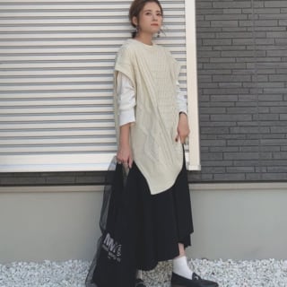 ニットベストと黒のスカートを着用した女性