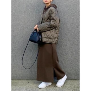 ブラウンダウンジャケットにブラウンワンピースを着た女性