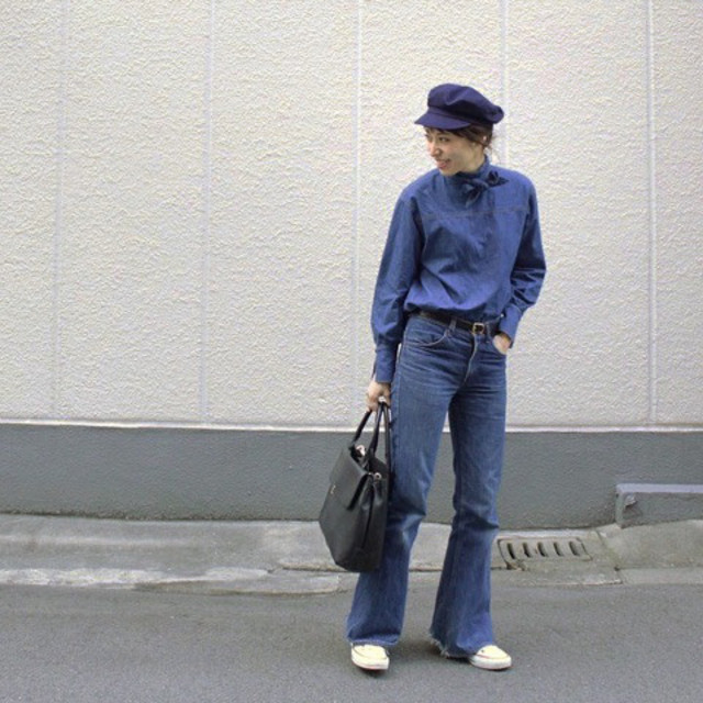 ブルーのシャツとデニムベルボトムパンツを履いた女性