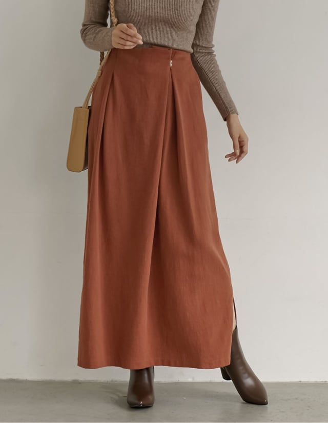 ブラウンニットにテラコッタのロングスカートを着ている女性の写真