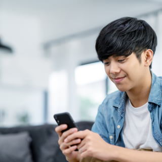 Happy asian teenager using smart phone