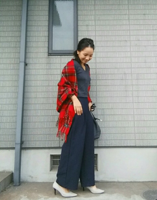 バギーパンツにグレーのプルオーバーを着てレッドスストールを羽織っている女性の写真