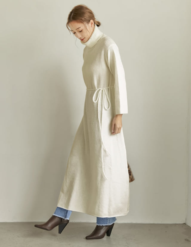 白いニットワンピースにフレアデニムを着ている女性の写真