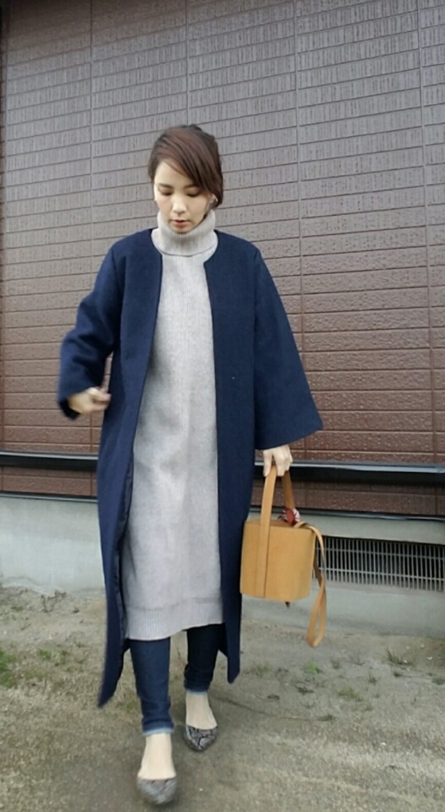 ニットワンピースにスキニーデニムを履いてネイビーのコートを着ている女性の写真