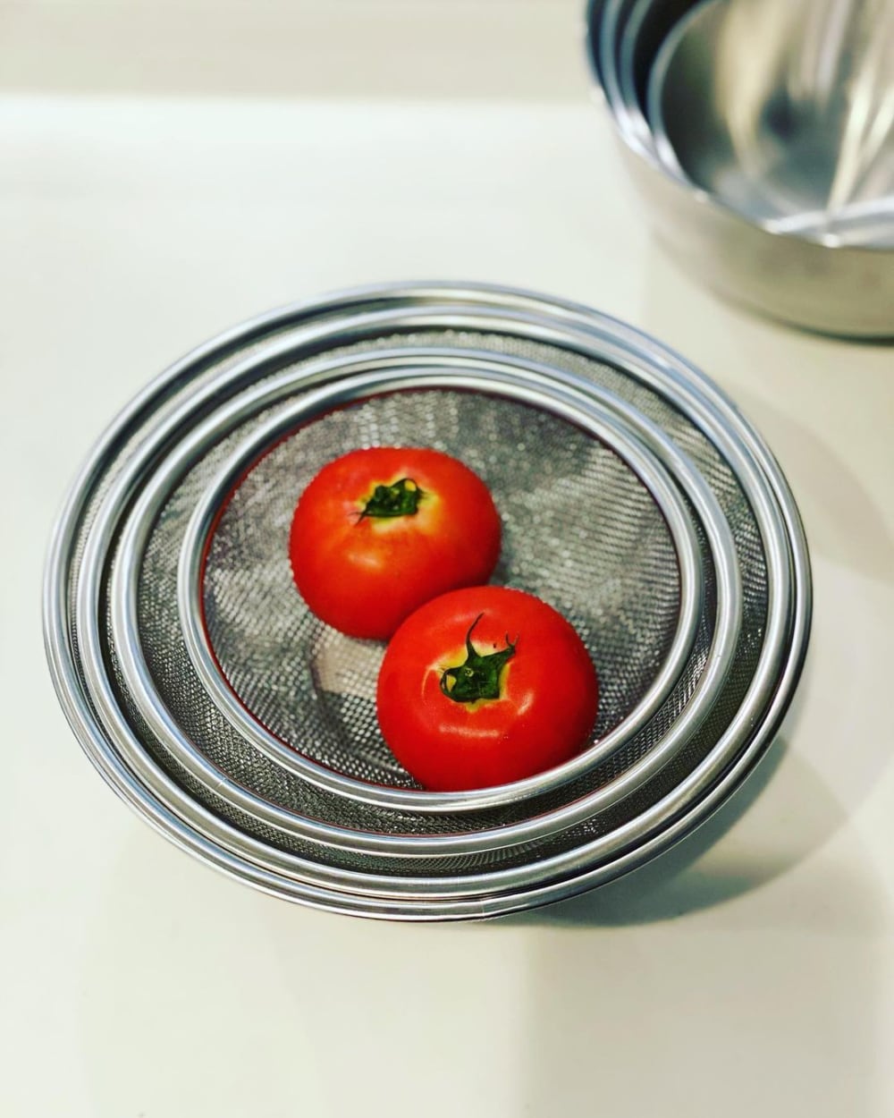 スリーコインズのザルにトマトを入れている写真