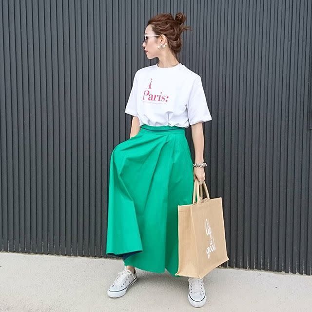 ロゴTシャツとグリーンのスカートを着用した女性