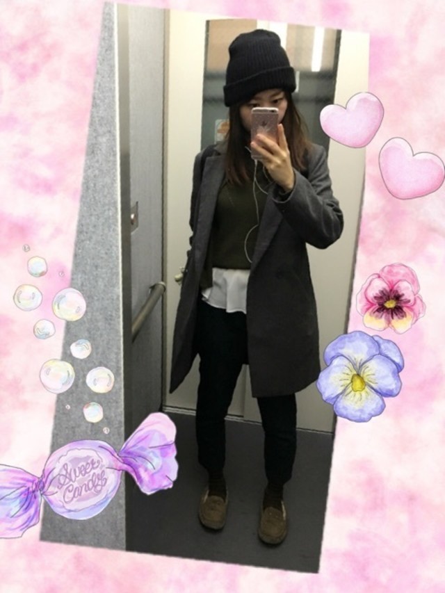 チェスターコートにカーキのニットと黒のテーパードパンツを着てUGGのモカシンを履いている女性の写真