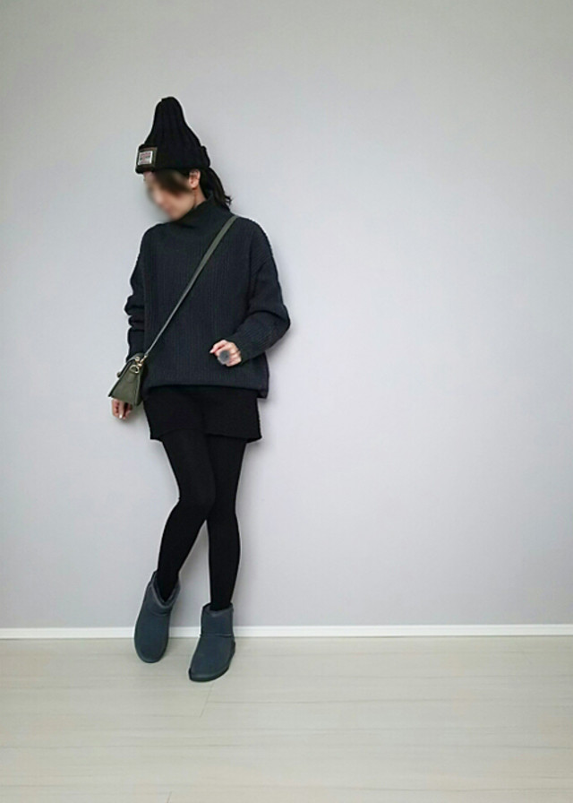 グレーのニットに黒のショートパンツを着てミネトンカのムートンブーツを履いている女性の写真